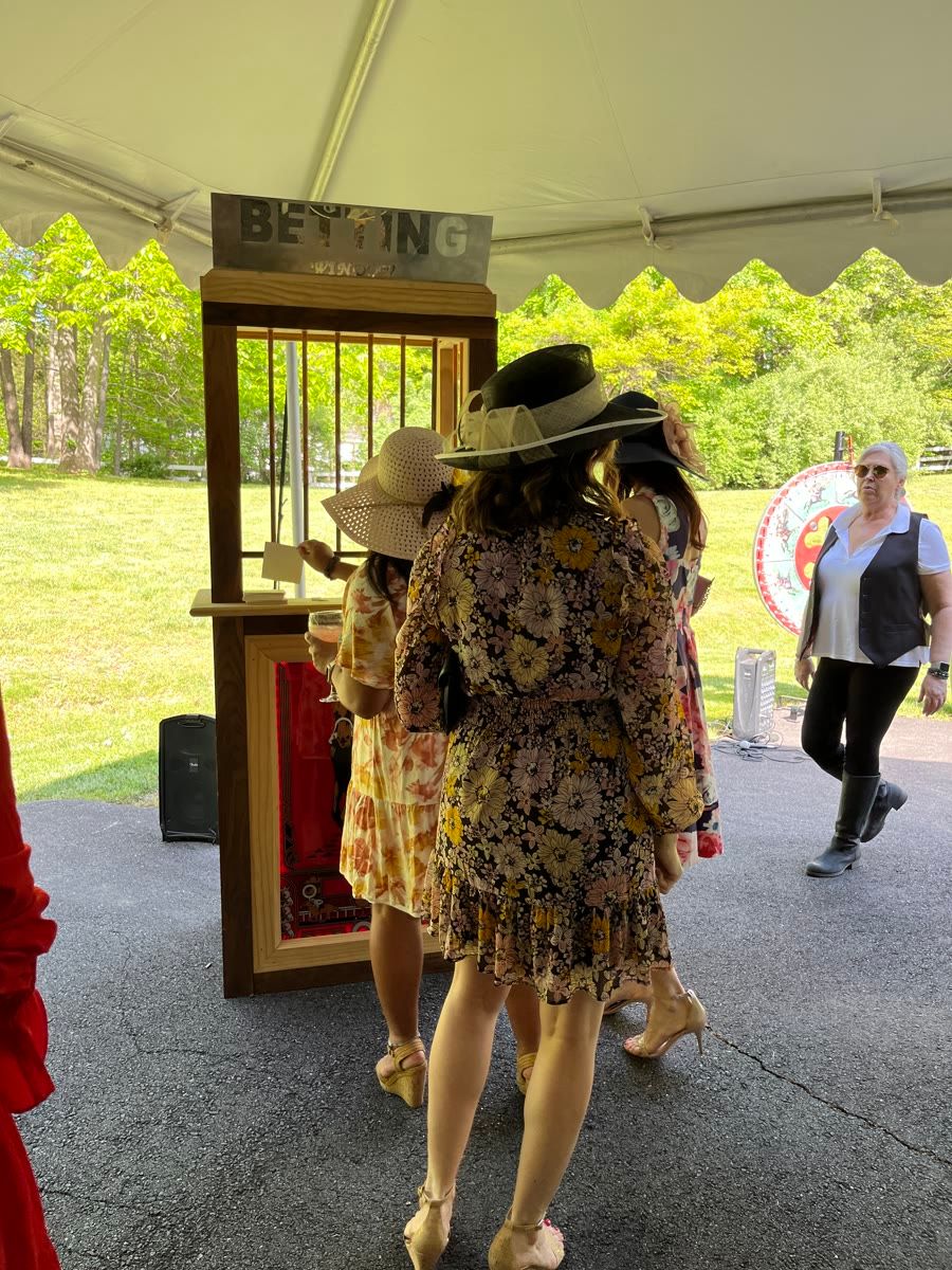 Guests in derby hats waiting at the Derby Dash betting window during a Metro Casino Events horse racing party.